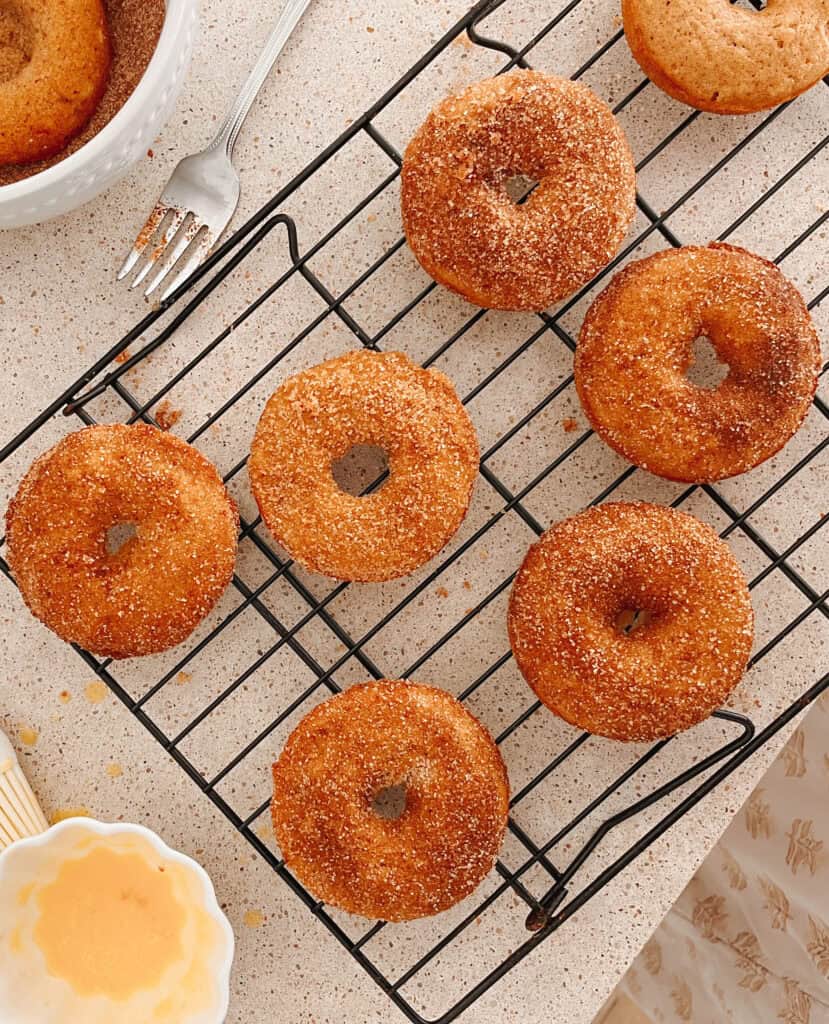 apple cider donuts on a wire rack after they have been dipped in cinnamon sugar