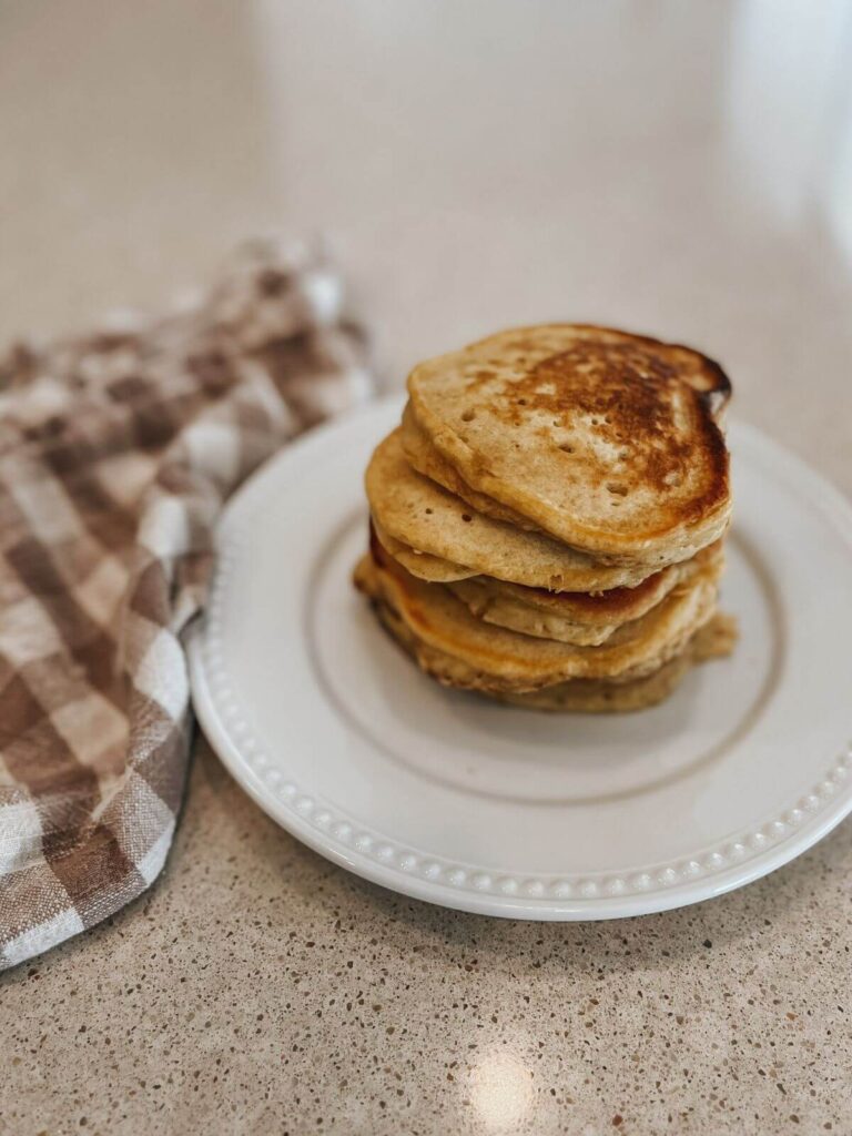 stacked pancakes straight from the pan on a white plate