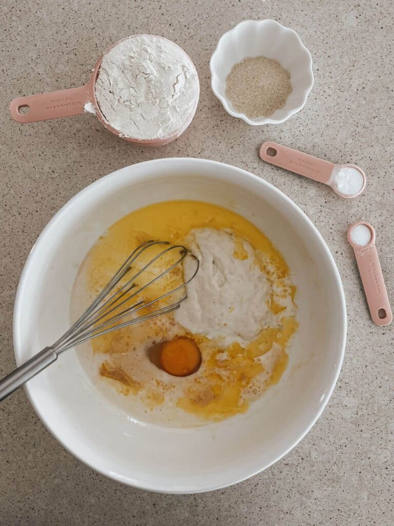 Mixing the wet ingredients for the pancakes in a white bowl with a whisk