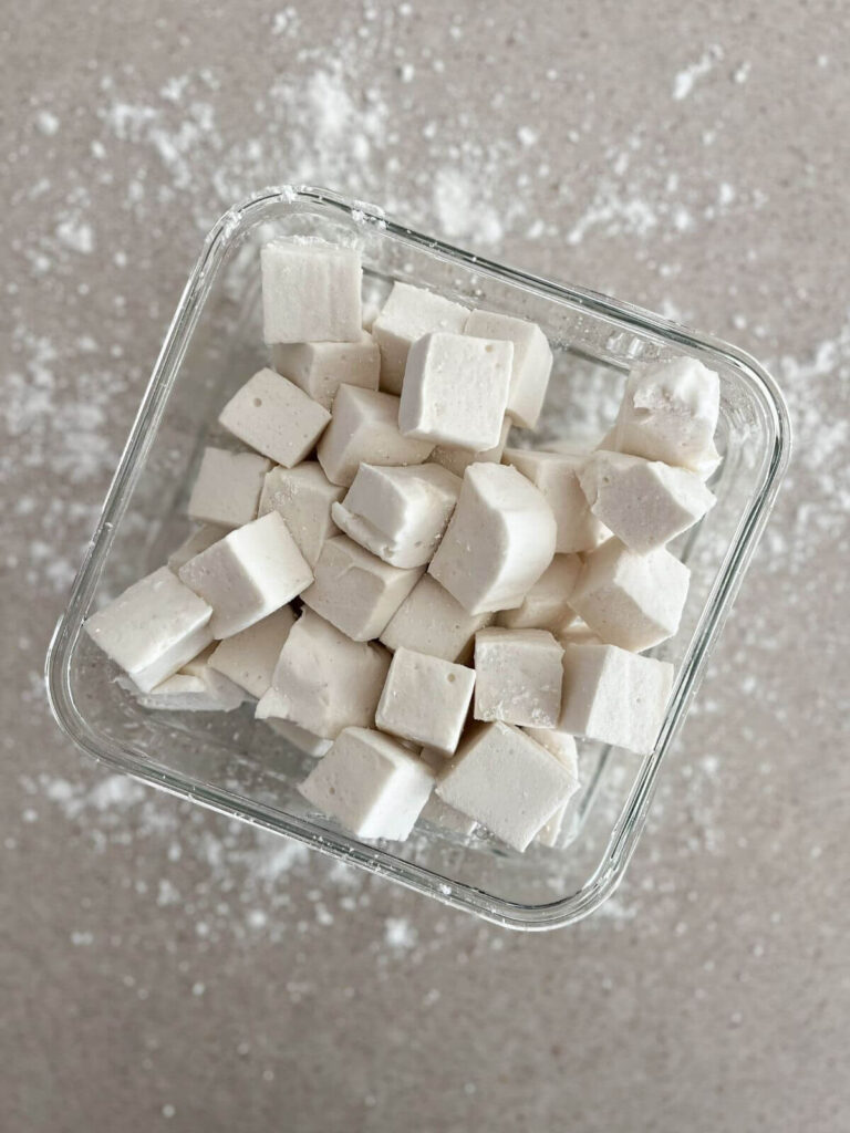 gut-friendly marshmallow stacked in a glass bowl with powdered sugar sprinkled around