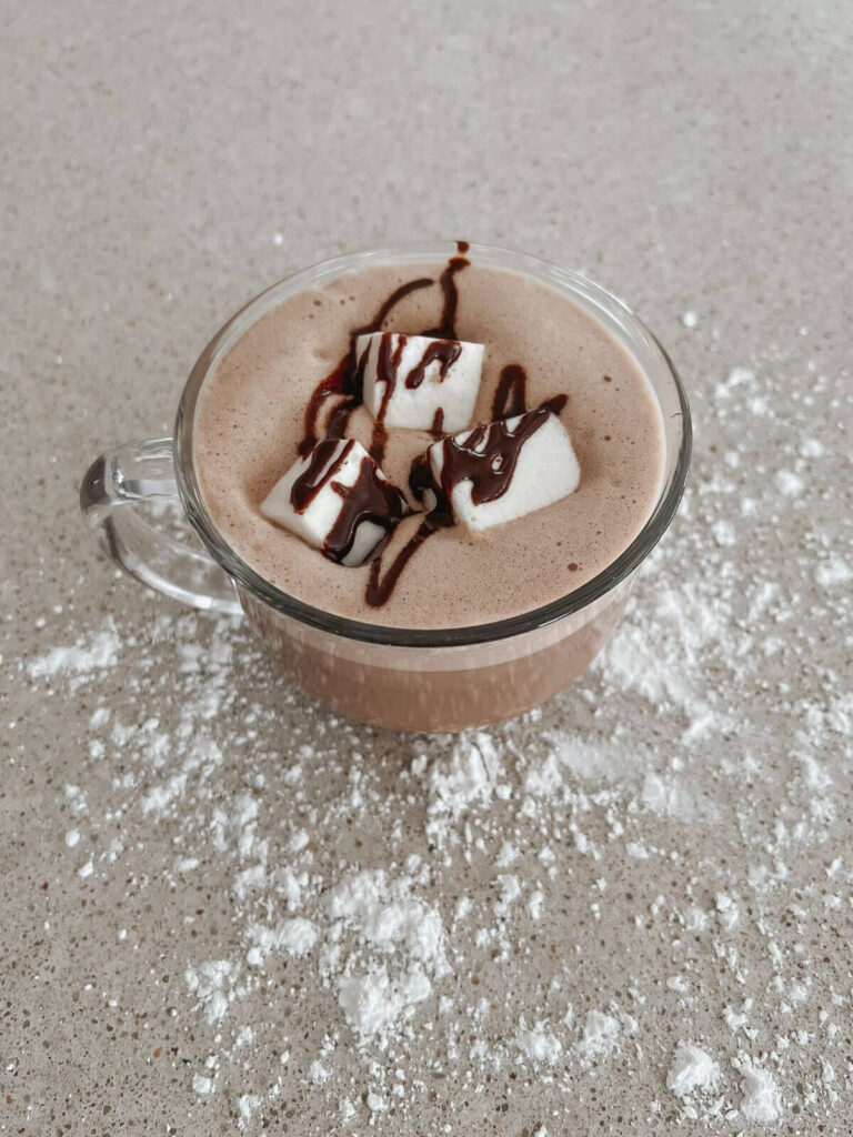 Top view of the hot chocolate with marshmallows and chocolate drizzle in a glass mug