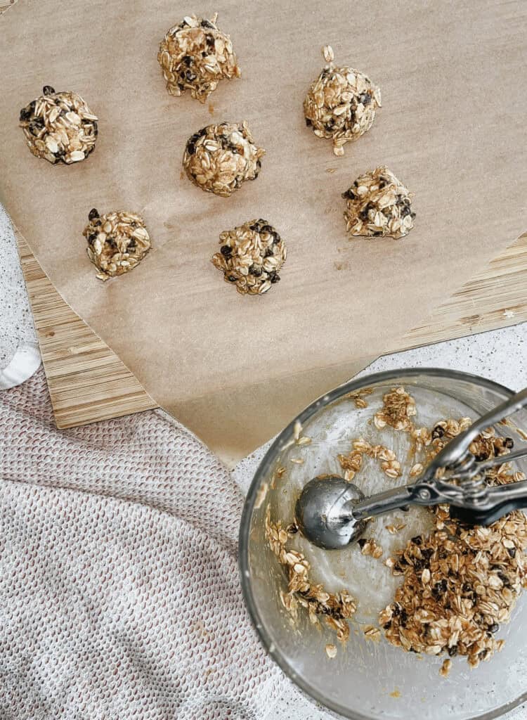 Action shot of the 5-ingredient Energy Bites being made with balls rolled out and some being scooped. 