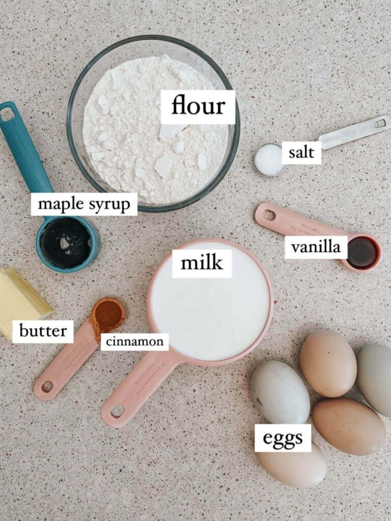 flatlay of the ingredients for the pancake: eggs, milk, cinnamon, vanilla, maple syrup, flour, salt, butter