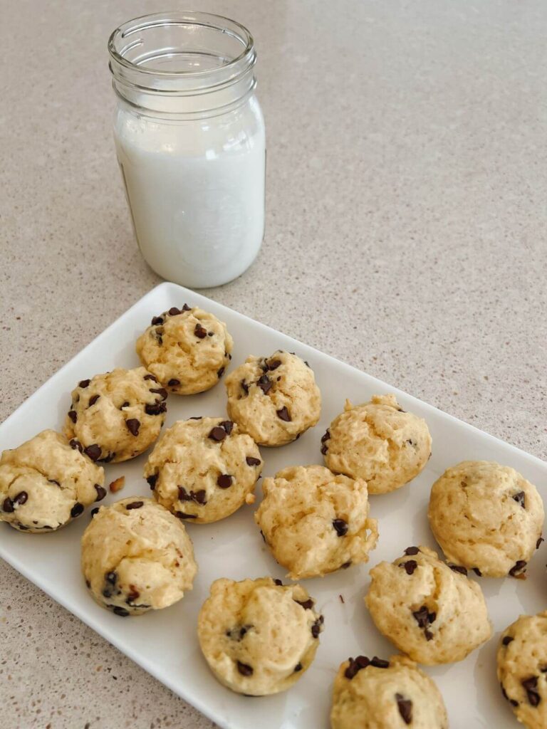 mini muffins on a white rectangular plate with a mason jar full of milk behind it. 