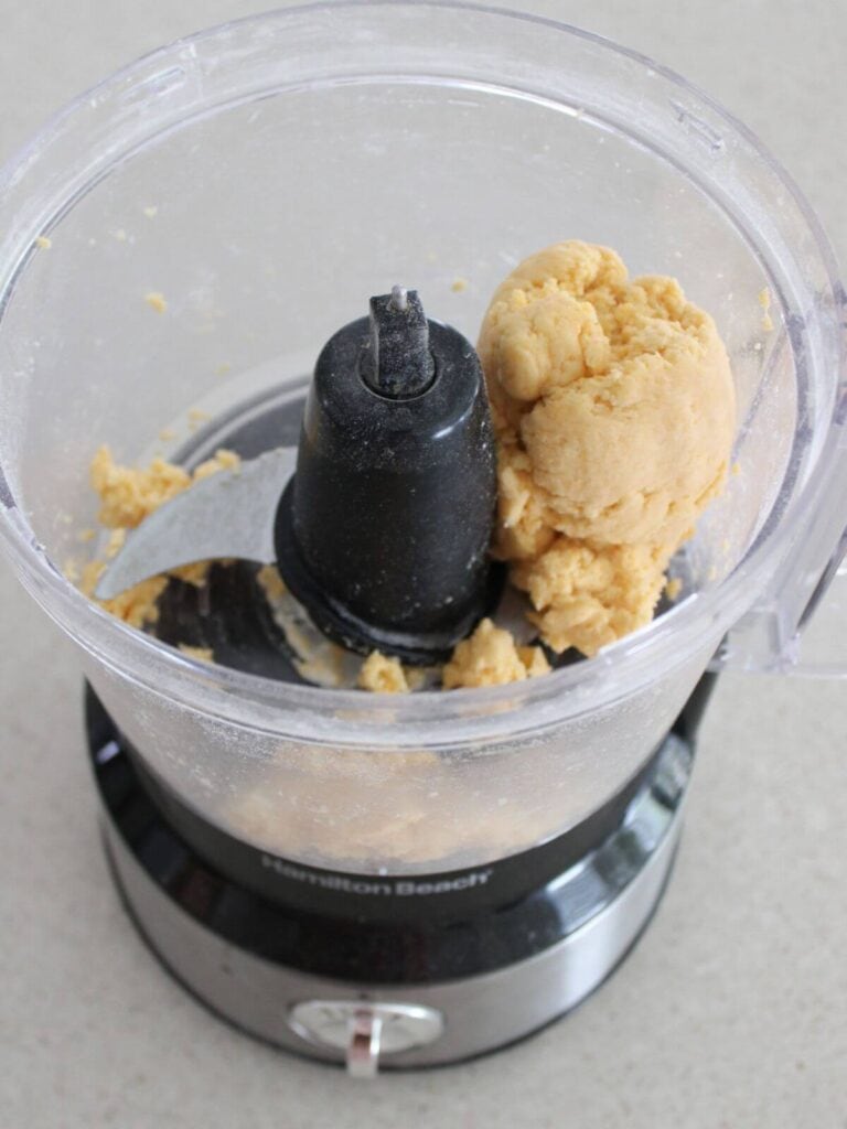 Adding water to dough until a ball forms in the food processor. 