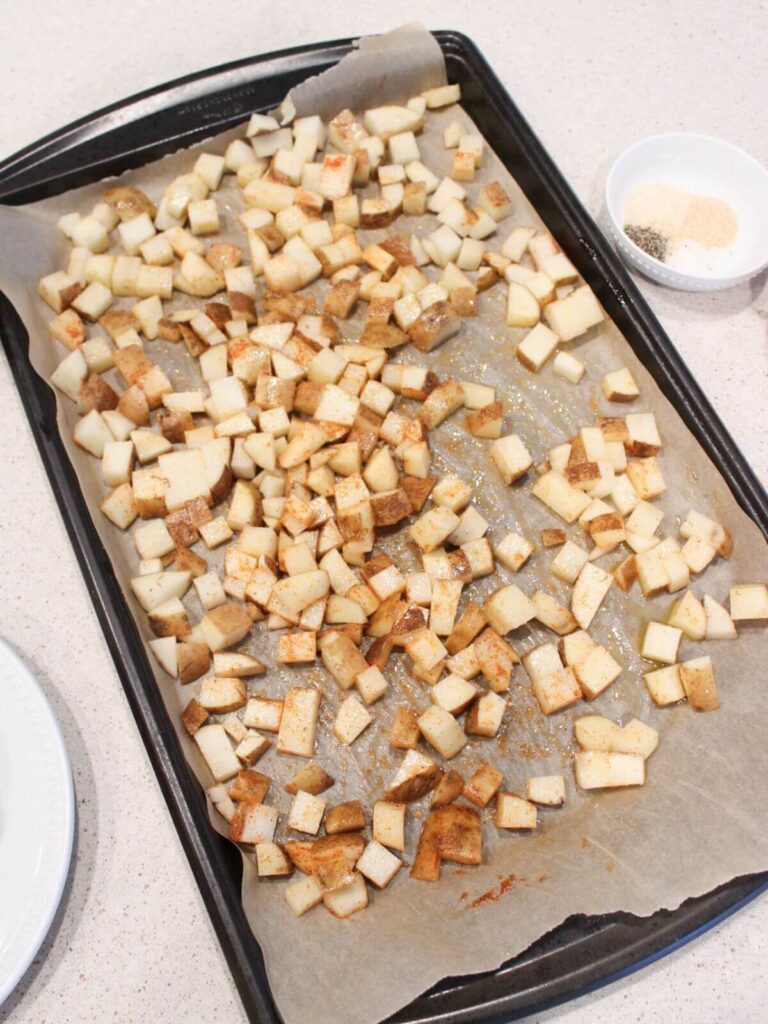 Potatoes ready to be roasted on a baking sheet with parchement paper. 