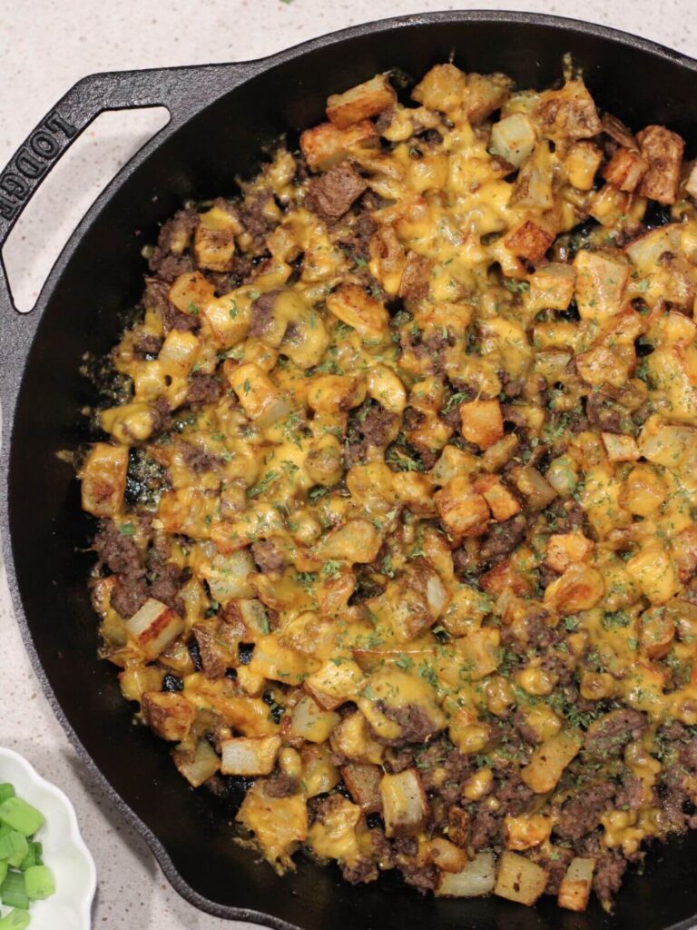 Easy potato bowl topped with melted cheese in a cast-iron pan ready to serve. 